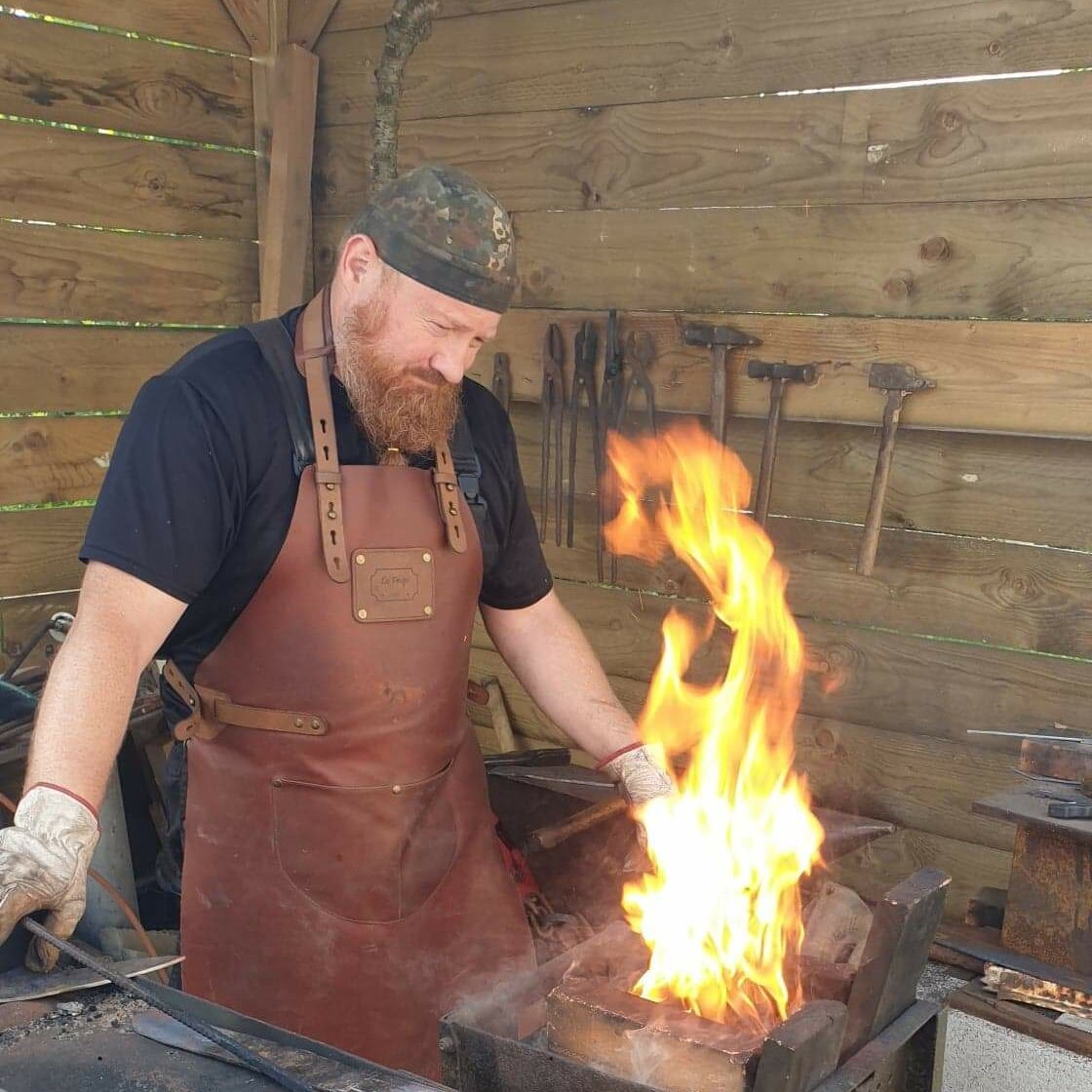 Sebastien devant la forge, une flame s'eleve grace à l'apport en air du soufflet.
Présentation de la forge 